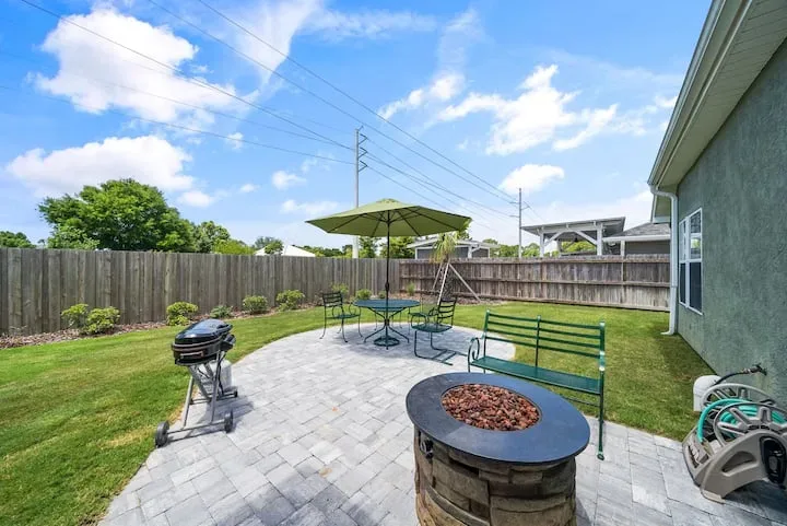 Fenced backyard patio with a fire pit, grill, and outdoor dining table
